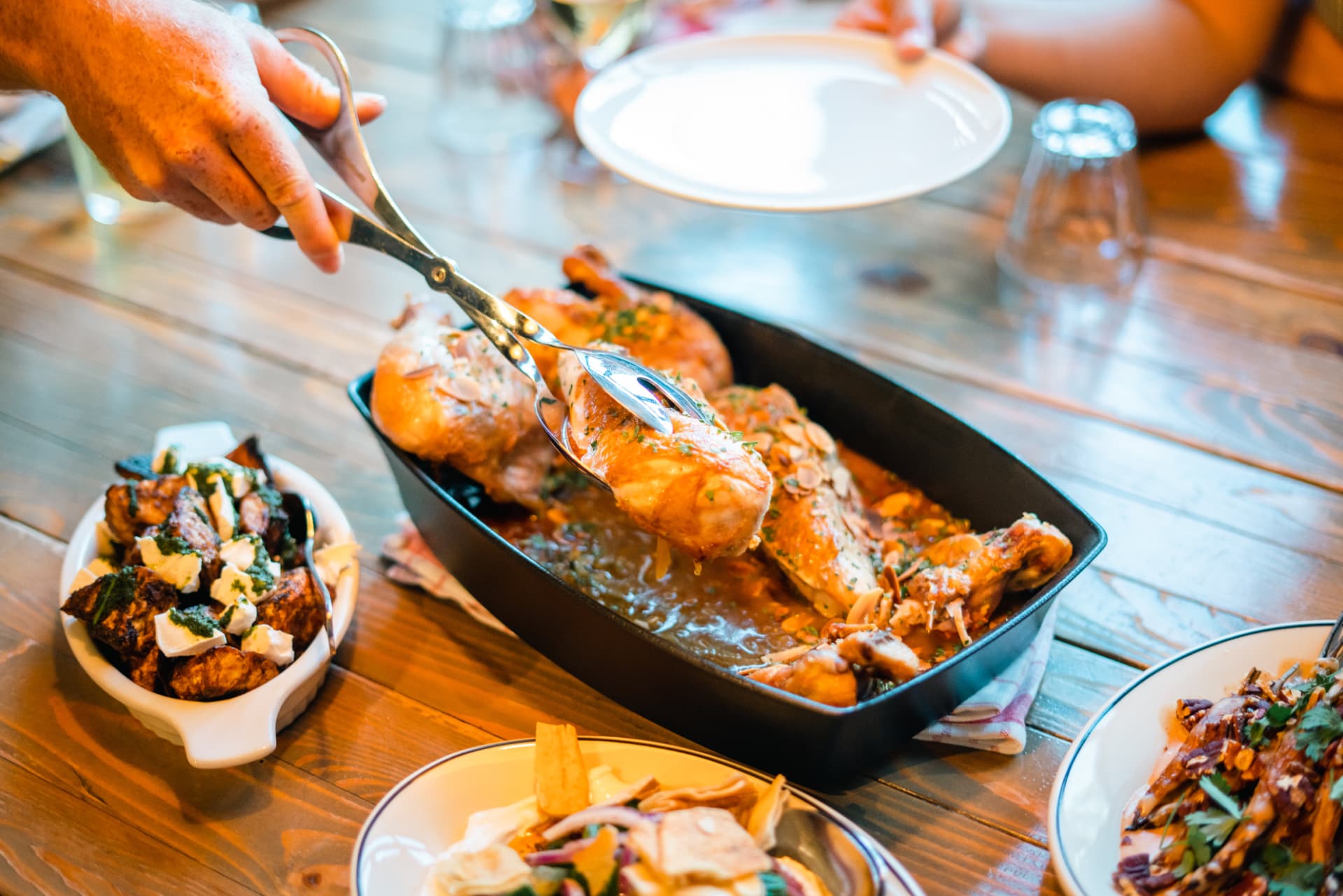 Poulet entier découpé à table, servi avec légumes rôtis