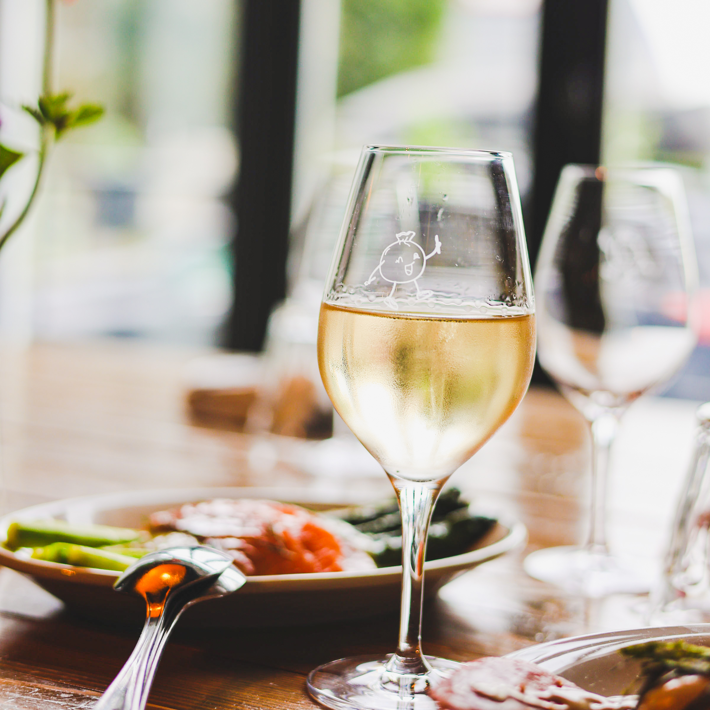 Un verre de vin blanc sur la table du BRUT., devant une assiette